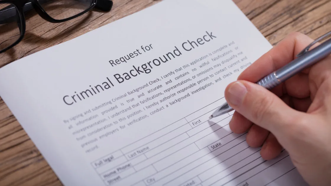A person filling out a criminal background check request form.