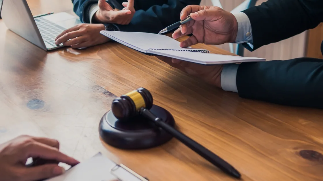 Attorneys reviewing case documents at a conference table beside a gavel.